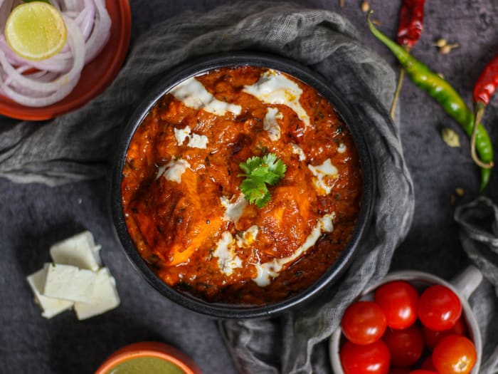 Butter chicken in a dark pan with a swirl of cream